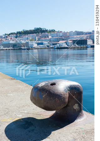 Close-up of a cast iron mooring bollard in the port of Vigo with the city and shipyards in the background. Close-up of a cast iron mooring bollard in the port of Vigo with the city and shipyards in the background. 138459294