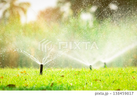 Automatic lawn sprinkler watering green grass. Sprinkler with automatic system. Garden irrigation system watering lawn. Sprinkler system maintenance service. Home service irrigation sprinkler. 138459817