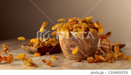 Yellow sultana raisins pour into a wooden bowl. Yellow sultana raisins pour into a wooden bowl. 138460859