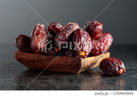 Dates fruit in wooden dish on a black background. 138460864
