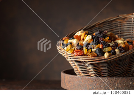 Mix of various nuts and raisins in a old basket on a brown background. 138460881