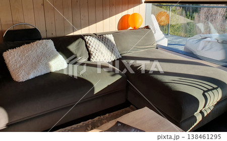 Cozy modern living room interior with soft sofa, decorative pillows and sun rays. Scandinavian style, wooden wall decoration and peaceful atmosphere in a country house Cozy modern living room interior with soft sofa, decorative pillows and sun rays. Scandinavian style, wooden wall decoration and peaceful atmosphere in a country house 138461295