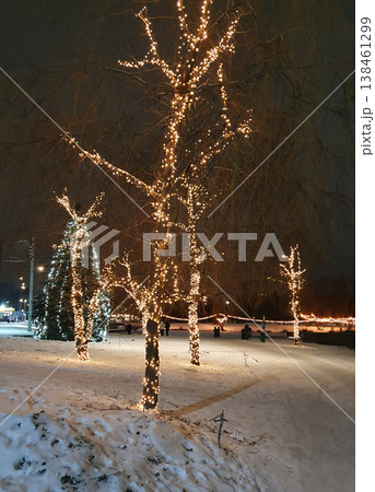 Winter city park in the evening, decorated with warm garlands on the trees. Snow on the ground, festive atmosphere of a winter night. For themes of Christmas, New Year, holidays coziness, winter walks Winter city park in the evening, decorated with warm garlands on the trees. Snow on the ground, festive atmosphere of a winter night. For themes of Christmas, New Year, holidays coziness, winter walks 138461299