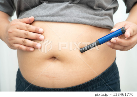 Asian woman injecting herself diabetes injecting insulin in stomach at home. 138461770