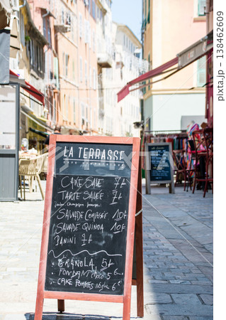 明るい日差しの下の店先に置かれたフランス語のメニューの看板　地中海に浮かぶフランス領のコルシカ島にて 138462609
