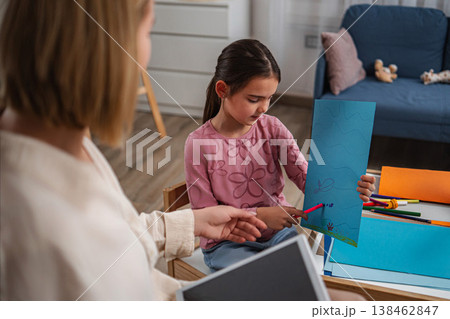 Child presenting drawing to pedagogue during art therapy session Child presenting drawing to pedagogue during art therapy session 138462847