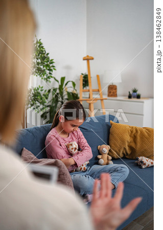 Unhappy girl receiving child therapy from psychologist Unhappy girl receiving child therapy from psychologist 138462849