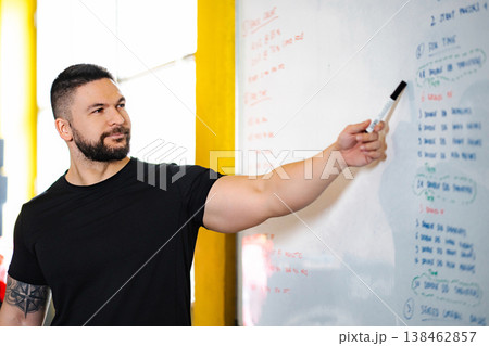 Fitness coach explaining workout plan on whiteboard Fitness coach explaining workout plan on whiteboard 138462857