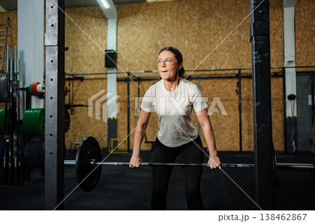 Woman doing weightlifting exercise with barbell in gym 138462867