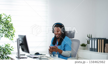 Medical professional using smartphone and headset at office desk 138462982