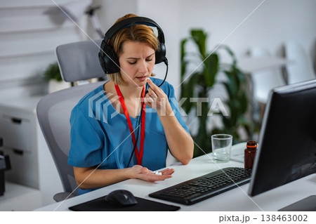 Stressed medical professional taking medication at office desk Stressed medical professional taking medication at office desk 138463002