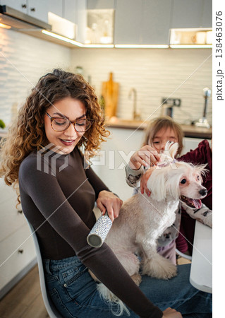 Mother and daughter grooming dog with lint roller in kitchen Mother and daughter grooming dog with lint roller in kitchen 138463076