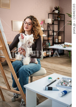Woman with dog painting on canvas in art studio 138463103