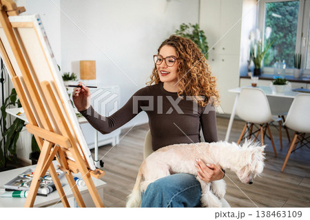 Woman painting on canvas with dog at home Woman painting on canvas with dog at home 138463109