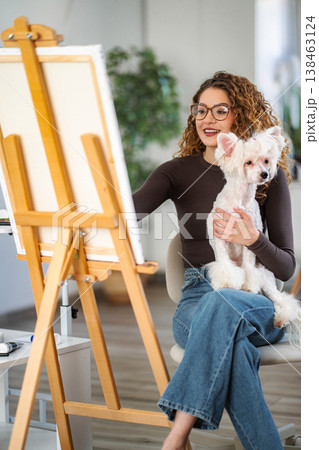 Woman painting on canvas with dog in comfortable home studio Woman painting on canvas with dog in comfortable home studio 138463124