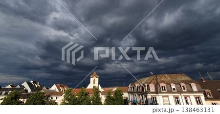 Phone photo of dramatic dark clouds over the rooftops of Strasbourg. Moody urban sky scene showing storm weather, architecture, and tense atmosphere. Phone photo of dramatic dark clouds over the rooftops of Strasbourg. Moody urban sky scene showing storm weather, architecture, and tense atmosphere. 138463131
