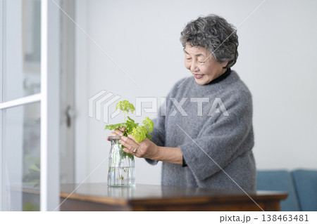 部屋に花を飾るシニア女性 138463481