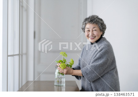 部屋に花を飾るシニア女性 カメラ目線で笑顔のポートレート 部屋に花を飾るシニア女性 カメラ目線で笑顔のポートレート 138463571