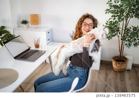 Woman embracing dog working from home with laptop 138463575