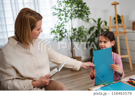 Woman giving drawing to cute young girl for art therapy 138463579