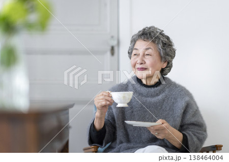 ティーカップを持ってほほえむ80代の女性 138464004