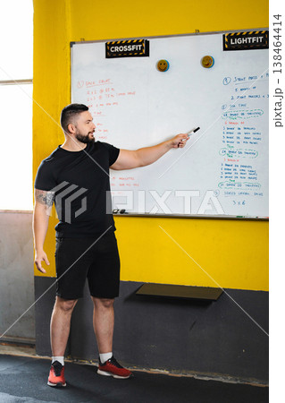 Fitness coach leading CrossFit workout explanation on whiteboard 138464414