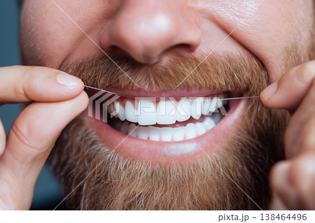 Man with healthy white teeth and beard confidently flossing for perfect oral hygiene and a bright smile Man with healthy white teeth and beard confidently flossing for perfect oral hygiene and a bright smile 138464496