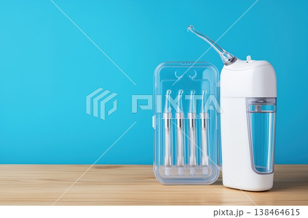 Portable oral irrigator and nozzle case on a wooden table 138464615