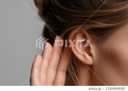 Woman with hair bun holds hand to her ear to listen and eavesdrop carefully 138464880