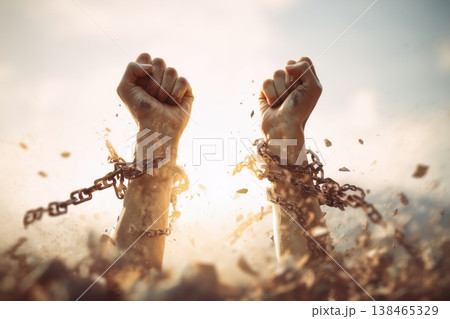 Hands raised break chains, freedom, empowerment and resilience concept shown in this conceptual stock material 138465329