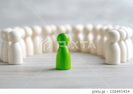 Green wooden figure stands out from a group, showcasing individuality, leadership, and unique perspective on a neutral background. 138465434