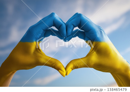Hands painted in Ukrainian flag colors forming a heart against a blue sky evoke themes of support and solidarity. Hands painted in Ukrainian flag colors forming a heart against a blue sky evoke themes of support and solidarity. 138465479