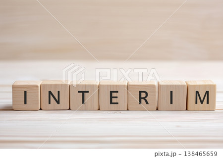 Wooden blocks spell interim on a light wooden surface representing transitional periods Wooden blocks spell interim on a light wooden surface representing transitional periods 138465659