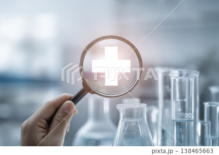 Magnifying glass focuses on a medical cross symbol within a laboratory setting for healthcare advancement. Magnifying glass focuses on a medical cross symbol within a laboratory setting for healthcare advancement. 138465663