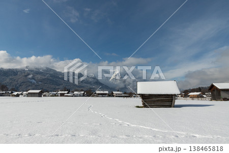 Snowy barn with footprints leading across winter field toward alpine mountain in Bavaria Snowy barn with footprints leading across winter field toward alpine mountain in Bavaria 138465818