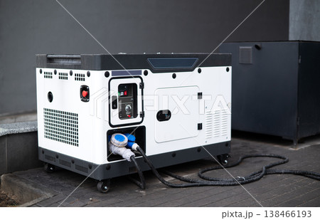 Portable diesel generator with power cables outdoors near building, backup electricity equipment Portable diesel generator with power cables outdoors near building, backup electricity equipment 138466193