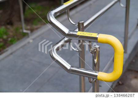 Stainless steel handrail with braille markings and yellow safety coating, accessibility infrastructure outdoors 138466207