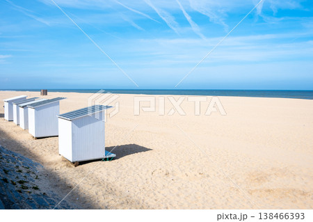 White holiday beach cabins on the beach. Blue sky with sun, yellow sand and beautiful sea for summer vacation. Wood houses. Ostend, Belgium. 138466393