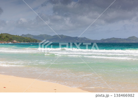 Turquoise ocean waves gently roll onto a wide beach 138466982