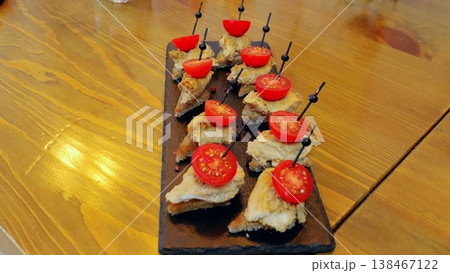 Gourmet canapes with toasted crostini, tuna mousse, cherry tomatoes elegantly plated on black slate, resting atop rustic wooden surface Gourmet canapes with toasted crostini, tuna mousse, cherry tomatoes elegantly plated on black slate, resting atop rustic wooden surface 138467122