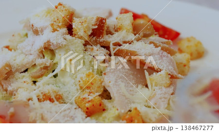 Crisp romaine leaves topped with grilled chicken strips, golden croutons, shaved parmesan, ripe tomato chunks in classic caesar salad composition 138467277