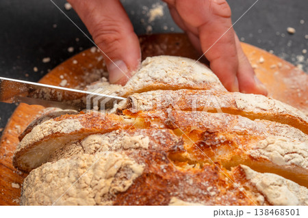 Closeup of sliced artisan sourdough bread with knife and hands 138468501