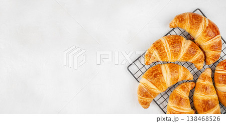 Fresh croissants on cooling rack on a light background. copy space, top view Fresh croissants on cooling rack on a light background. copy space, top view 138468526