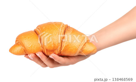 Woman hand holding fresh croissant isolated on light background with copy space 138468569