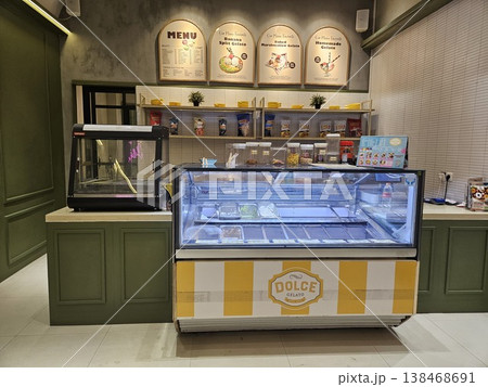 Interior view of a modern gelato shop featuring a glass display freezer with various ice cream flavors 138468691