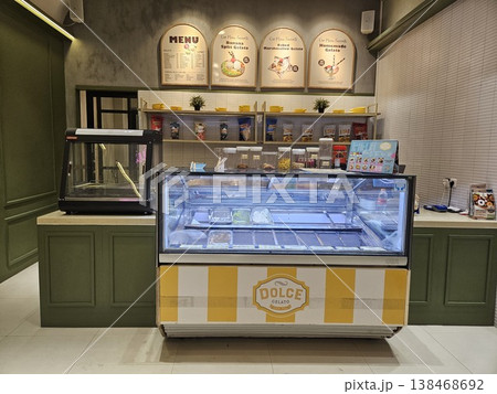 Interior view of a modern gelato shop featuring a glass display freezer with various ice cream flavors 138468692
