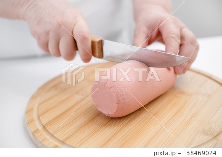 Women's hands cutting sausage on a board 138469024