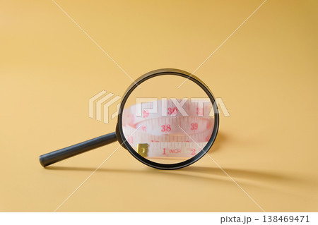 A magnifying glass and measuring tape on background. A magnifying glass and measuring tape on background. 138469471