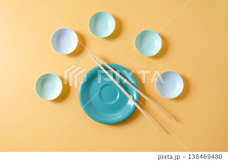Plate and Chopsticks and small bowls on color background. Plate and Chopsticks and small bowls on color background. 138469480