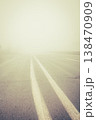 Foggy empty highway. Bad weather on the road. Road on foggy day in perspective with copy space. Driving conditions concept. Caution and danger on the road. Road marking lines on ghostly route. 138470909